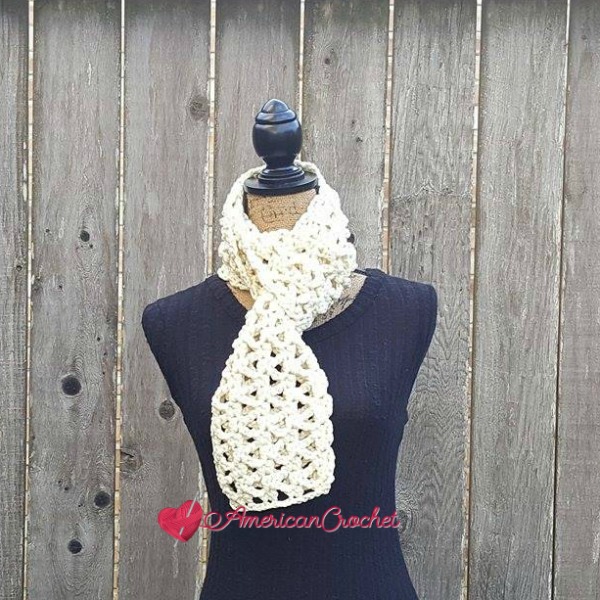 A mannequin wearing an off-white lacy crochet scarf.