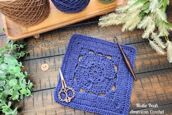 Acquaintance Square crochet pattern – a textured 9-inch square featuring single, half double, double, treble crochet stitches, and back loop only rows. Shown flat with crochet hook and scissors, part of the Riverwood Square CAL 2025 by American Crochet.
